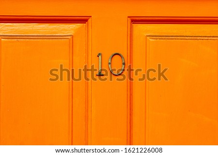 House number 10 on an orange wooden front door in London