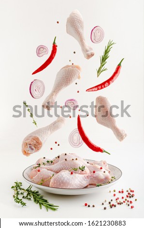 Spicy marinated raw chicken legs or drumsticks levitation. Flying food concept. Royalty-Free Stock Photo #1621230883