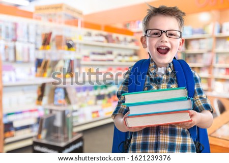 Little schoolboy in glasses with books on background Royalty-Free Stock Photo #1621239376