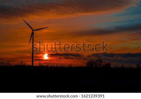 Wind power plant in sunset, photo is like silhouette. Wind electricity - renewable as environmentally sustainable. In the background sun and sky with clouds.