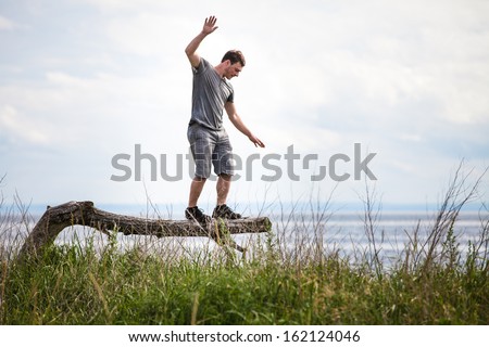 Young Adult Balancing on a dead Tree in Nature.