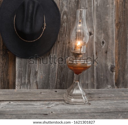 horizontal photo of a black cowboy hat and oil lamp on a rustic wood background