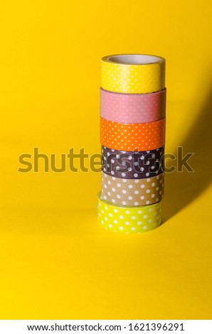 tall line of colorful washi tapes isolated on yellow background. school stationery