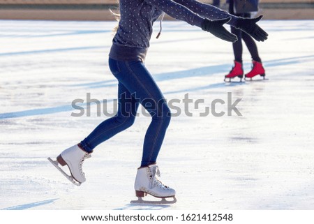 legs of a girl in blue jeans and white skates on an ice rink. hobbies and leisure. winter sports

