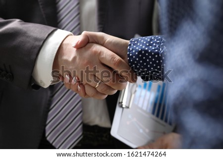 Close-up of businessman and businesswoman handshaking. Partners signing important and profitable agreement, contract. Business meeting and negotiations concept