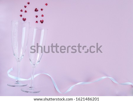 Valentines day composition. Flat lay with two champagne glasses with red hearts out and white ribbon on pink background. Top view. copy space. Valentine day, wedding, birthday concept. Greeting card