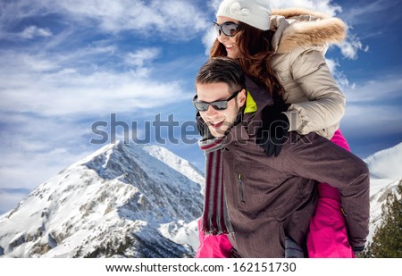 couple on winter vacation, young man piggybacking his girlfriend
