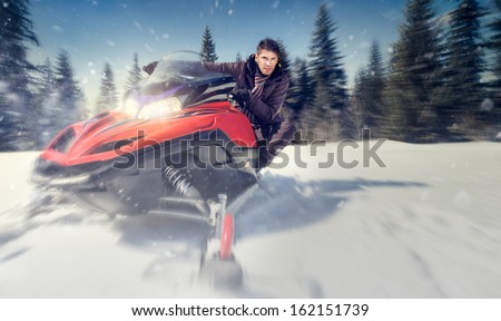 young man driving  snowmobile at beautiful winter day - in motion 