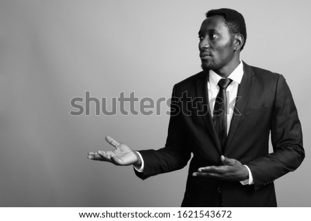 Young handsome African businessman against gray background