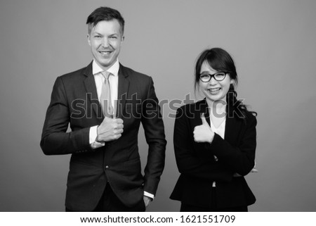 Young multi ethnic business couple working together against gray background