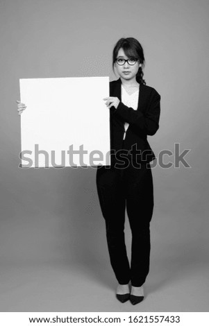 Young beautiful Asian businesswoman against gray background