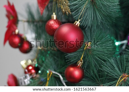 Closeup of red bauble hanging from a decorated Christmas tree with bokeh, copy space, Xmas holiday background.