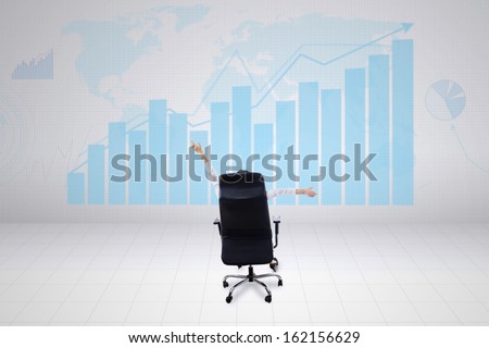 Successful businesswoman sitting on chair and looking at growth graph