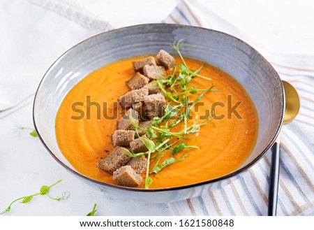 Pumpkin soup in a bowl served with croutons and pea sprouts. Vegan diet soup. Vegetarian food.