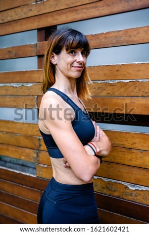 Portrait of cheerful female athlete posing in front of a wooden background