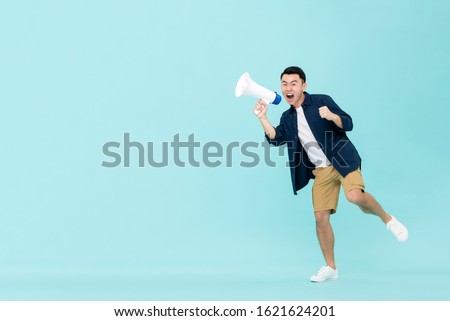 Excited young Asian man holding megaphone and shouting isolated on light blue background with copy space Royalty-Free Stock Photo #1621624201