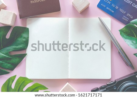 Top view of blank space white notebook and pen with travel gear such as passport, camera, credit card and  wall as frame of picture background. 