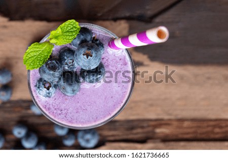Blueberry smoothie purple colorful fruit juice milkshake blend beverage healthy high protein the taste yummy In glass drink episode morning on a wooden background from top view.
