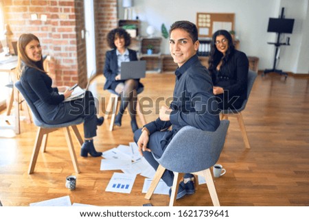 Group of business workers smiling happy and confident. Sitting on chairs relaxed with smile on face. Working together reading documents and speaking at the office