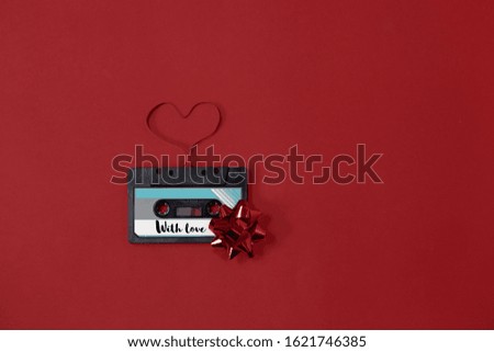 Valentines day card audio cassette with magnetic tape in shape of heart on red background.