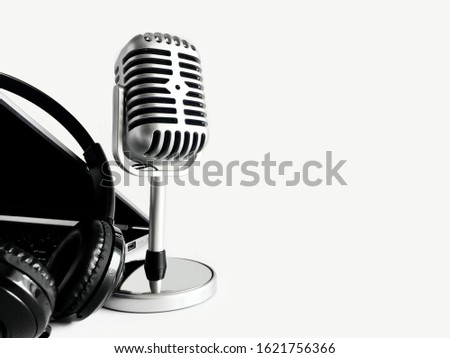 Background of audio equipment on the left side of the light gray background, including a retro microphone, a headphones and a laptop.   