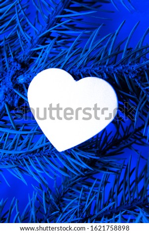 White heart on a blue background with a fir branch. Color of the year 2020