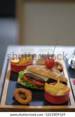 Hamburger served on a wooden board with side dishes