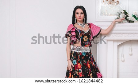portrait of an attractive young Gypsy woman standing near a decorative fireplace