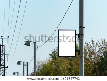 Billboard.Street poster of white color on a metal pole. on the background of power lines and green trees.Place for text, advertising of goods and services.Template. Empty layout, horizontal.