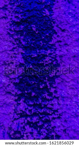 Purple flowed paint on a rough wall.
