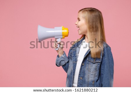 Side view of little blonde kid girl 12-13 years old in denim jacket posing isolated on pastel pink background children portrait. Childhood lifestyle concept. Mock up copy space. Scream in megaphone