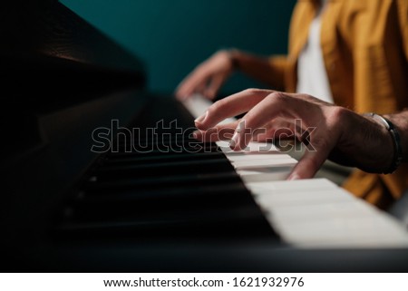 Male hands playing keyboard at the studio