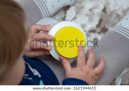 A child independently tries to open a plastic bottle of medicine, close-up. Child-resistant, childproof or CR packaging. Push&Turn Cap. Child safety concept Royalty-Free Stock Photo #1621944610