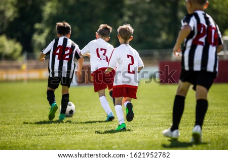 Young Boys In Football Teams Running in Duel After Soccer Ball