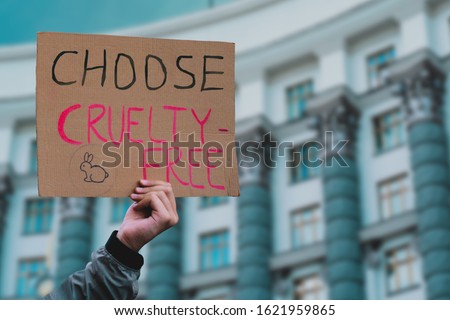 The phrase " Choose cruelty free " on a banner in men's hand. Animal rights protest. Protection. City. Urban. Rally. Freedom. Stop animal testing. Equality. Justice. Care. Life. Humanity Royalty-Free Stock Photo #1621959865