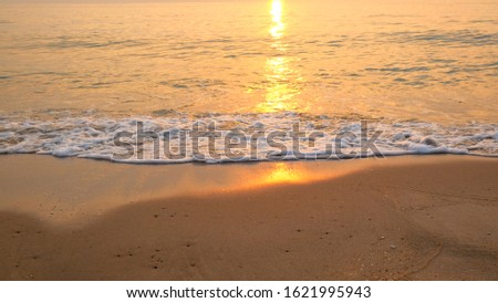 Reflection form sunrise on surface sea water on beach background.