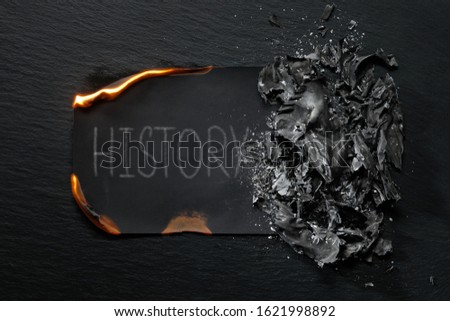 Burning piece of black paper with the word "HISTORY "on a black background.