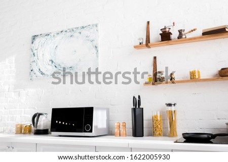 microwave, electric kettle, pasta, knives, pepper mill, salt mill on surface in kitchen