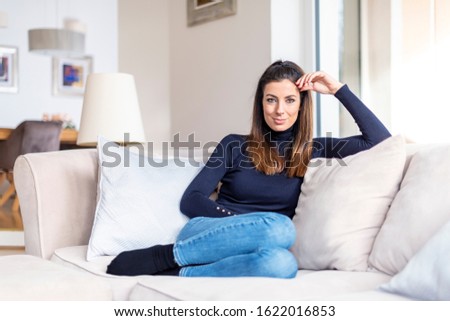 Ful length shot of attractive woman resting on comfortable sofa at home.