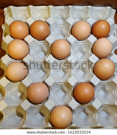 Close-up view of raw brown chicken eggs in egg box on wooden background   which arranged in heart picture 