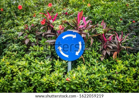 Roundabout road sign in shrub plant. It is in mandatory signs group.