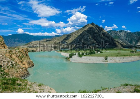 Beautiful view of bend in Katun river with blue bky and clouds in the Altai mountains. Amazing landscape of the river and high mountains in sunny summer day.