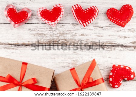 Valentines Background with Handmade Sewed Pillow Hearts Row Border from Red Fabric, Gift Boxes with Red Ribbon at Rustic White Wood Background. Concept of Happy Valentine's Day. Copy Space