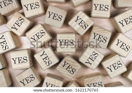 words yes composed of wooden cubes with letters, concept of choice, scattered around the cubes random letters, top view on wooden background Royalty-Free Stock Photo #1622170765