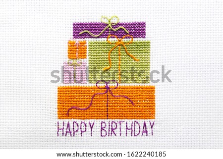 The inscription Happy birthday and gift boxes are embroidered on a white canvas.