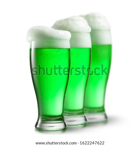 Three glasses of green alcoholic drink with thick foam on a white background , copy space. Happy St.Patrick 's Day concept.