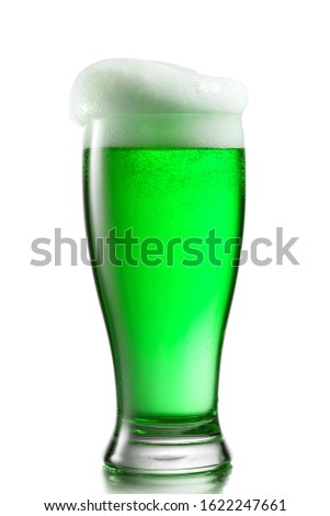 Closeup view of clear glass with fresh natural alcoholic beer drink and extra foam on a white background, copy space. Happy St.Patrick 's Day concept.