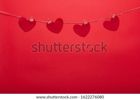 Decorative clothespins with hearts on a rope on a red background for Valentine's Day, wedding, birthday and other holidays, view from the top.