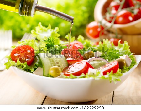 olive oil pouring into bowl of salad Royalty-Free Stock Photo #162229250