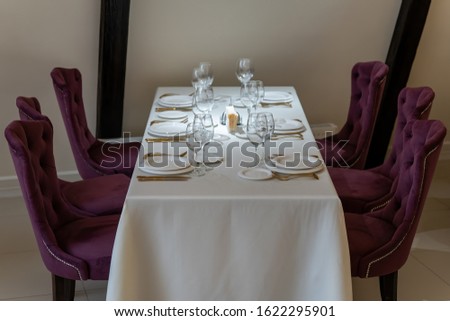Chic and elegant, gold-plated cutlery and white plates, table setting with empty plates. Luxury restaurant, preparation for the celebration. Beautiful glasses and wine glasses. Front view.